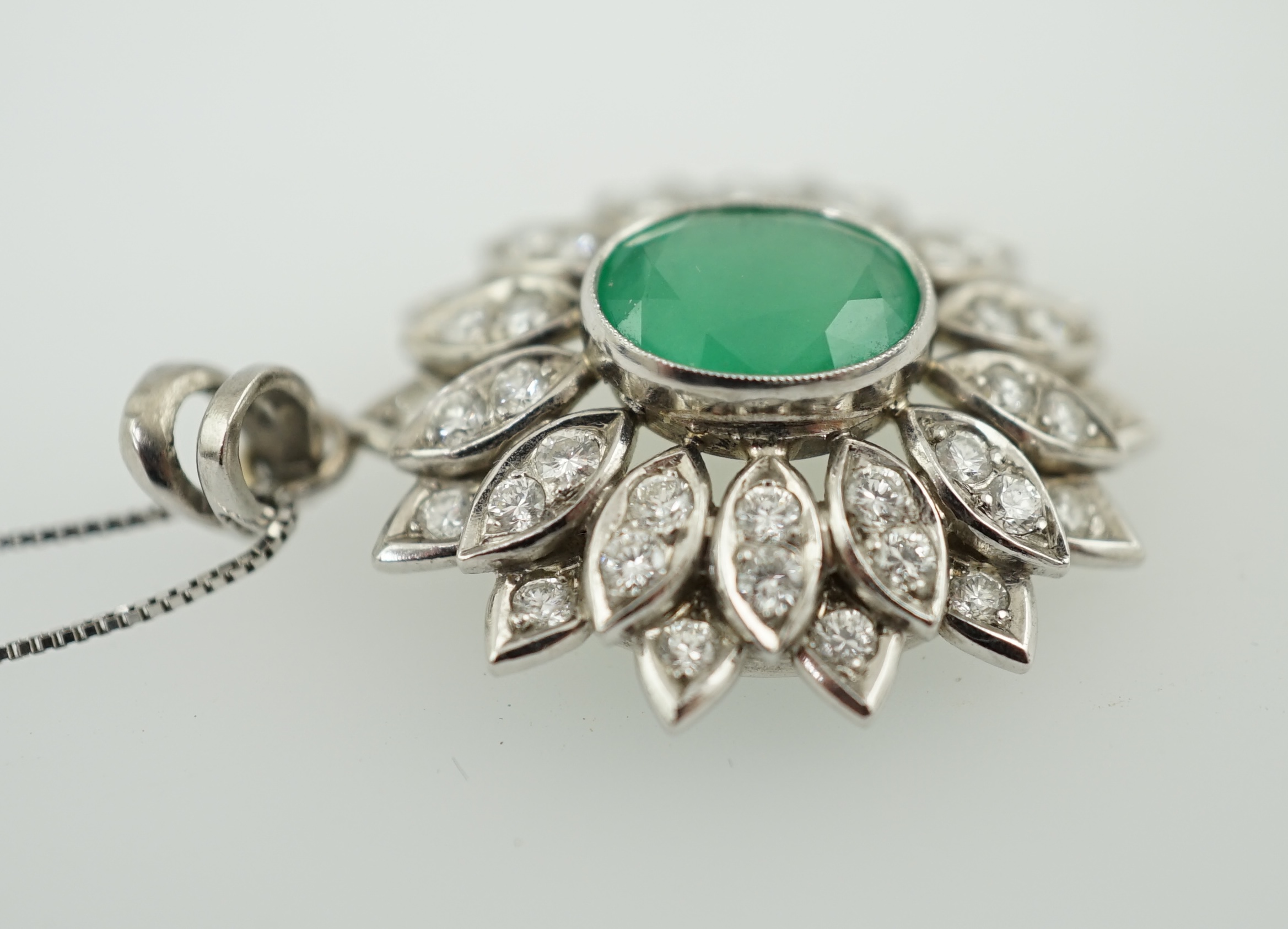 A modern platinum, emerald and diamond cluster set oval pendant